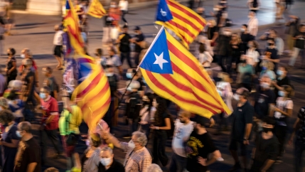 People hold a Catalonian independence flag, as they march during a demonstration to mark the fourth anniversary of a failed independence referendum, in Barcelona, Spain, late Friday, Oct. 1, 2021.