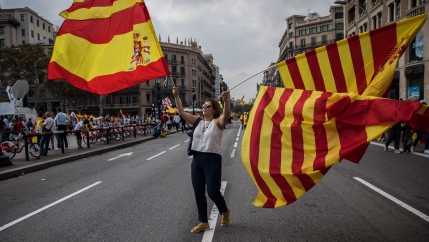 A woman waves flags of Catalonia and Spain as people celebrate a holiday known as 