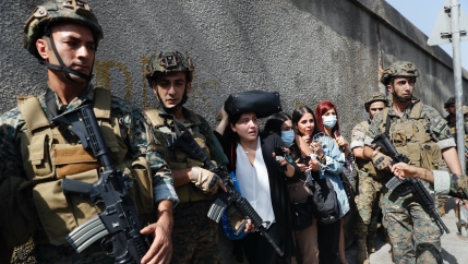 Lebanese teachers react to the sounds from nearby armed clashes as they flee their school under the protection of Lebanese soldiers after a clash erupted along a former 1975-90 civil war front line between Muslim Shiite and Christian areas at Ain el-Ruman