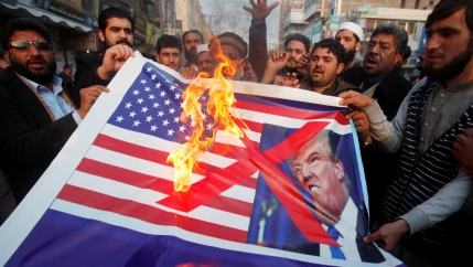 People burn a sign depicting a U.S. flag and a picture of U.S. President Donald Trump as they take part in an anti-U.S. rally in Peshawar, Pakistan, January 5, 2018.