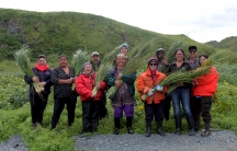 a group of people in a field holding traditional grass baskets