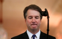 US Supreme Court nominee judge Brett Kavanaugh is shown looking down at a microphone.