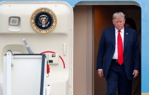 US President Donald Trump is shown exiting Air Force One with the door of the aircraft ajar.