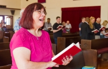 Woman in church holding book and singing