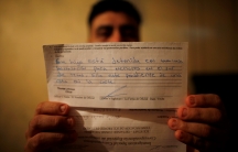 Letter from US government in focus, being held up by a man who is out of focus behind it