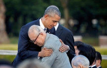 An older Japanese man hugs former President Barack Obama