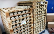 Rows of greenish-brown soap sit on wooden racks