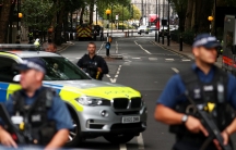 Police officers armed with riffles and bullet-proof vests stand at a cordon after a car crashed outside the Houses of Parliament in Westminster.