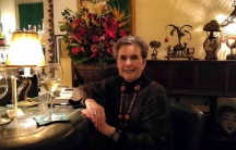 Kathy Kriger sitting at a bar next to a glass of wine