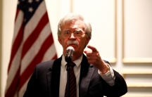 National Security Adviser John Bolton is shown at a microphone with the US flag behind him, speaking at a forum in Washington, DC, 2018.