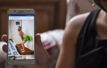 Lawrence Alatrash, 25, a non-binary gay Syrian refugee, shows a photo of himself on his mobile phone dressed up in a green tutu for last year's gay pride parade in downtown Athens, Greece.