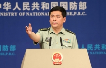 Chinese Defense Ministry spokesman Ren Guoqiang is shown at a podium with his arm outstretched.