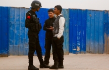 A Chinese police officer talks to men in a street in the city of Kashgar, in the Xinjiang Uighur Autonomous Region of China, on March 24, 2017.