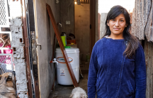 a woman in buenos aires stands in front of her informal home