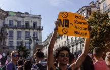 a man holds a protest sign in Lisbon