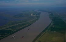 The Mississippi River as seen from flying above in an airplane shows several boats carrying goods.