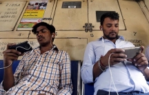 Commuters watch videos on their mobile phones