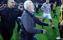 van Savvides is pictured with what appears to be a gun in a holster as he rushes on to the soccer field in Greece.