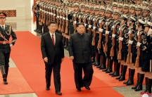 North Korean leader Kim Jong-un and Chinese President Xi Jinping walk past an rifle-clad honor guard.