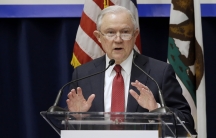 Man at microphone speaking with hands up