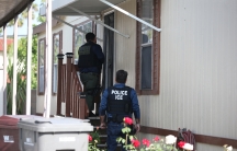 ICE agents knock on a door.