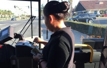Woman putting bills in public bus machine, with windshield behind her