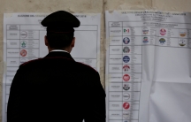 An Italian policeman looks at an electoral poster at a polling station in Rome, March 4, 2018.