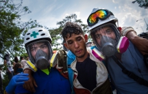 In Venezuela, two volunteers help a protester overcome by tear gas. The volunteers are mostly medical students who provide first aid at the anti-government demonstrations.