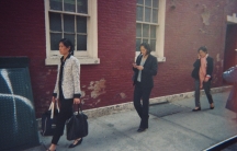 Three women walking on the sidewalk.