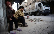 Children watch as an aid convoy of Syrian Arab Red Crescent drives through the besieged town of Douma, Eastern Ghouta, Damascus, Syria March 5, 2018.