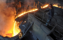 A worker monitors molten iron pouring into a furnace at steel manufacturing plant in Hefei, Anhui province, China. 