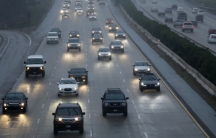 Cars move in the rain along a highway
