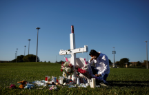 Joe Zevuloni mourns in front of a cross placed in a park to commemorate the victims of the shooting at Marjory Stoneman Douglas High School, in Parkland, Florida, Feb. 16, 2018.
