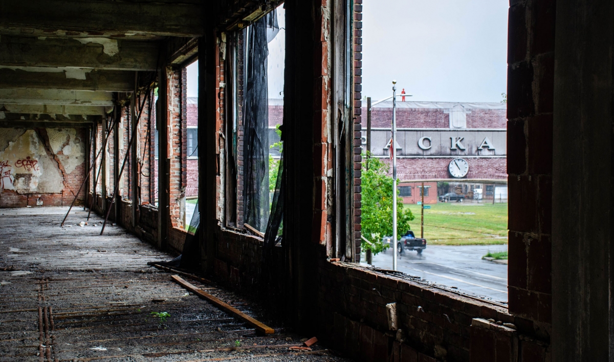 The lettering of the old Packard Plant in Detroit is seen on a brick bridge viewed through the ruins of a window in the factory.
