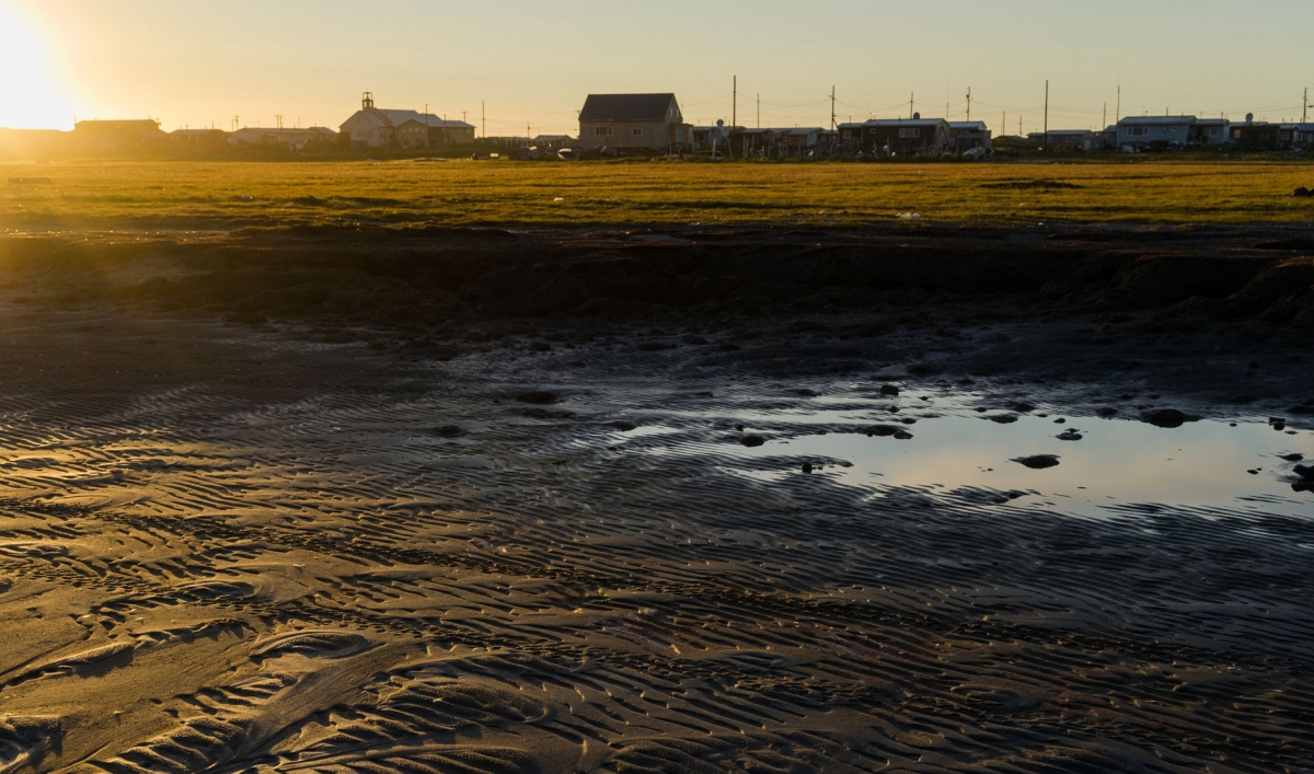 A person walks through a puddle in Shismaref, Alaska.