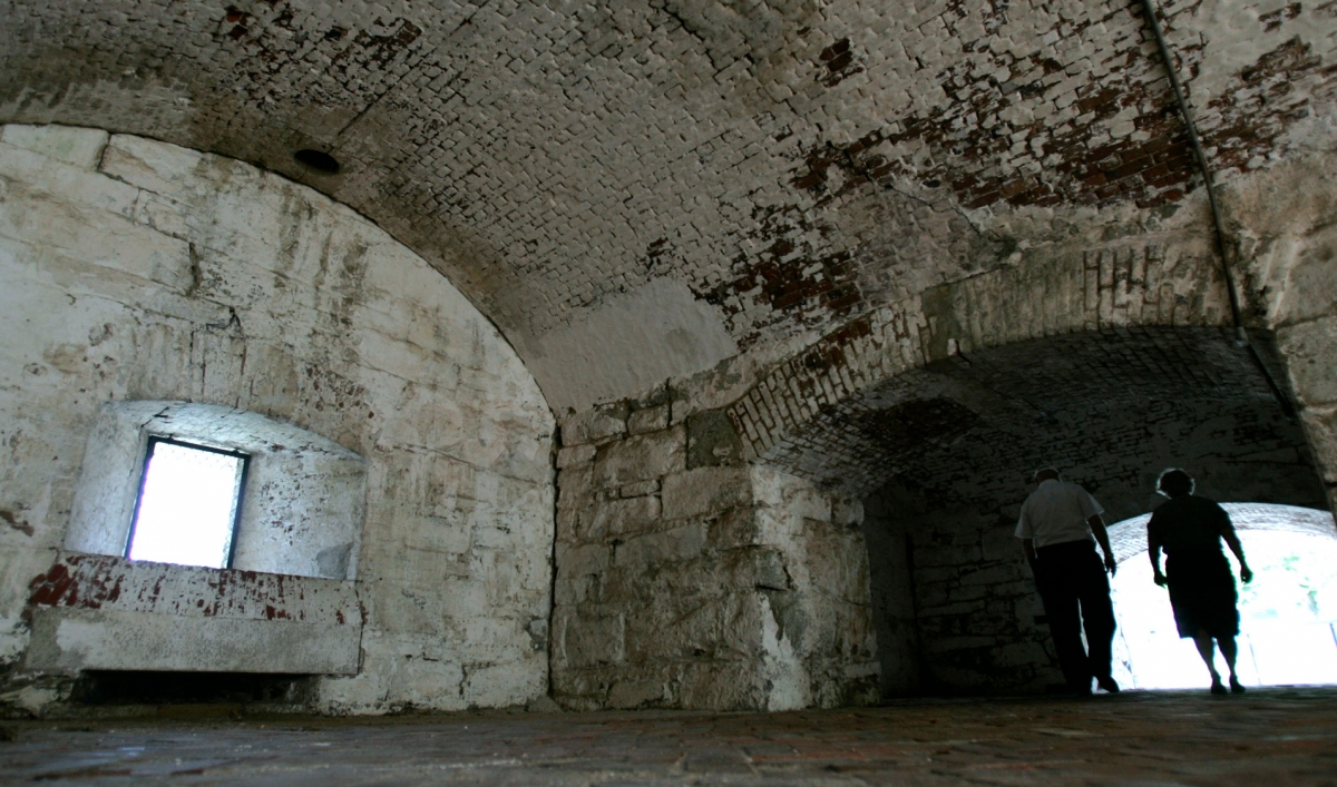 A couple is backlit against a stark stone fort interior.