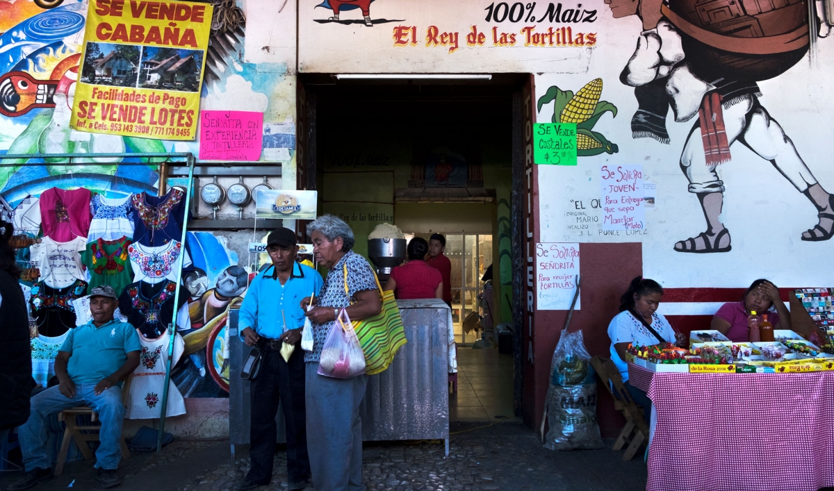 A market is shown in Tlaxiaco, Mexico, with vendors and shoppers.