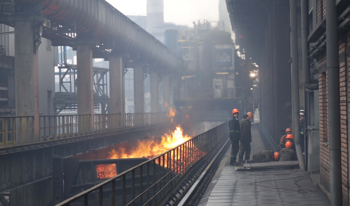 Industrial workers standing near burning coke fuel.