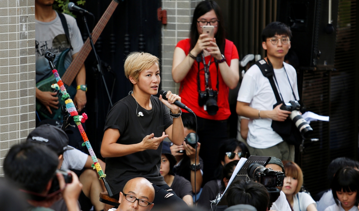 A woman holds a microphone in a crowd.