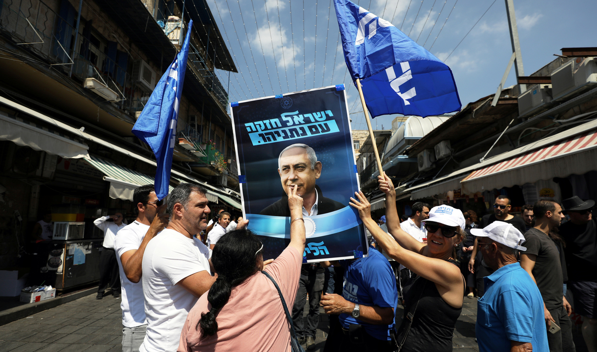 A supporter of the Israeli Likud party kisses an election campaign poster depicting Israel Prime minister Benjamin Netanyahu at the market in Jerusalem.