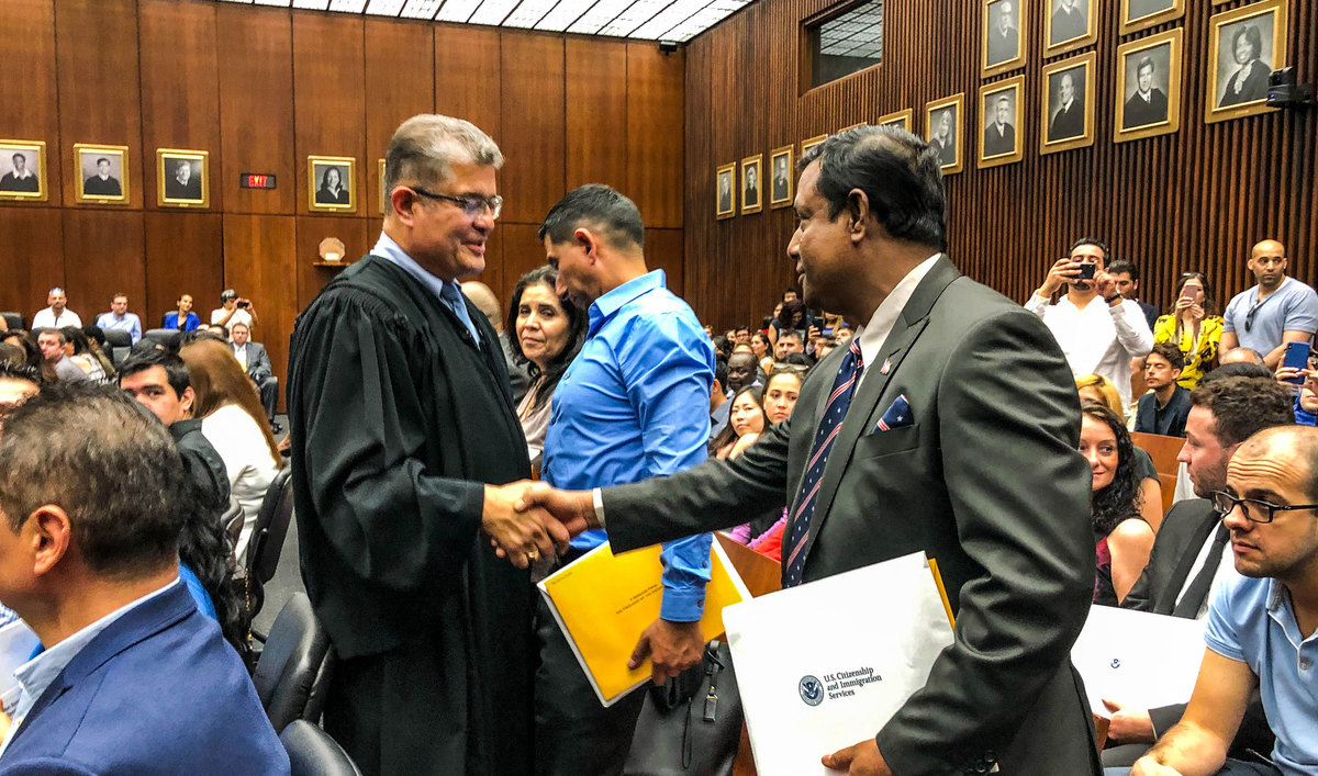 A judge shakes hands with a man at his citizenship ceremony