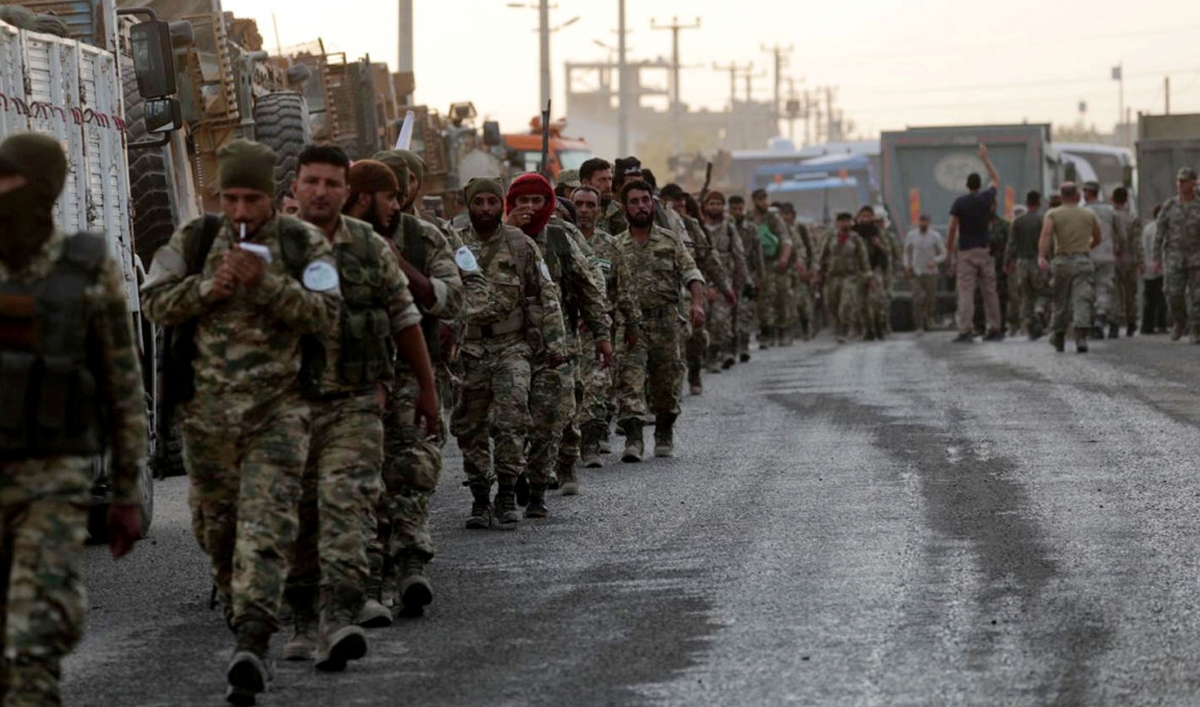 Turkey-backed Syrian rebel fighters walk together in the border town of Akcakale in Sanliurfa province, Turkey, on Oct. 11, 2019.