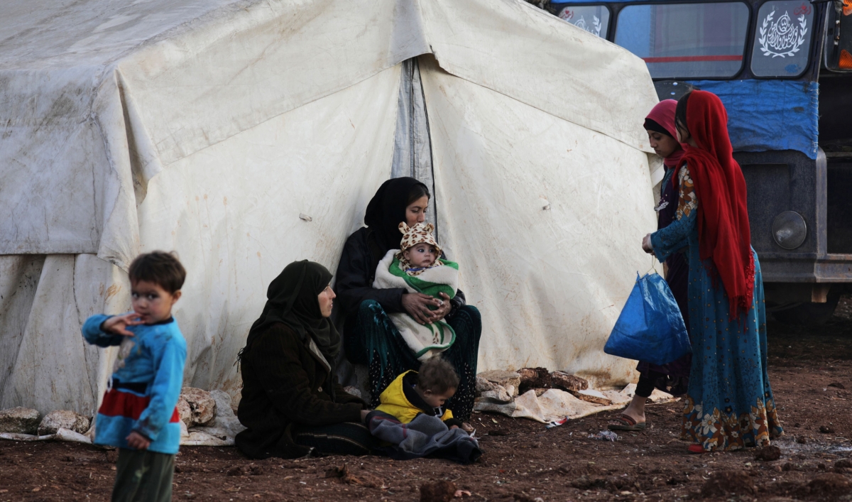 Internally displaced people stand outside tents at a makeshift camp in Azaz, Syria, Feb. 19, 2020.