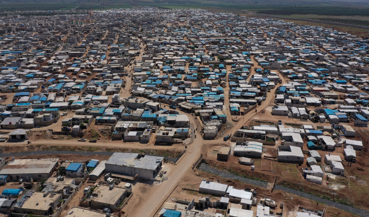 In this photograph taken from above, thousands of temportary shelters are shown across a wide arid area.