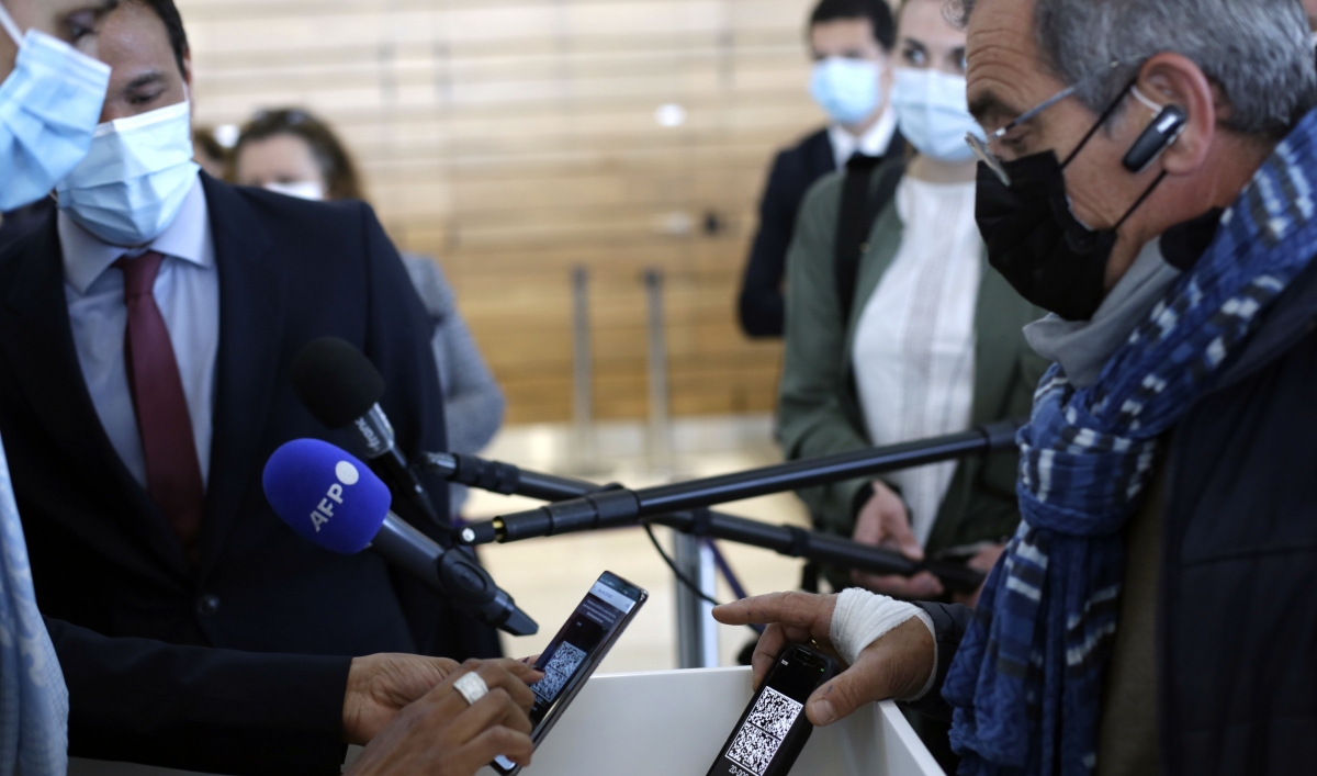 A passenger shows his PCR test result on his phone as he boards a plane at an airport