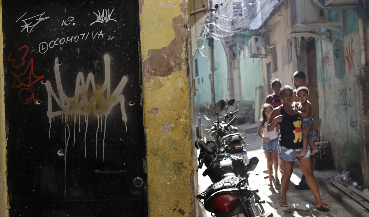 Residents walk near a doorway scared with bullet holes after a police raid against alleged drug traffickers in Rio de Janeiro, Brazil, May 6, 2021.