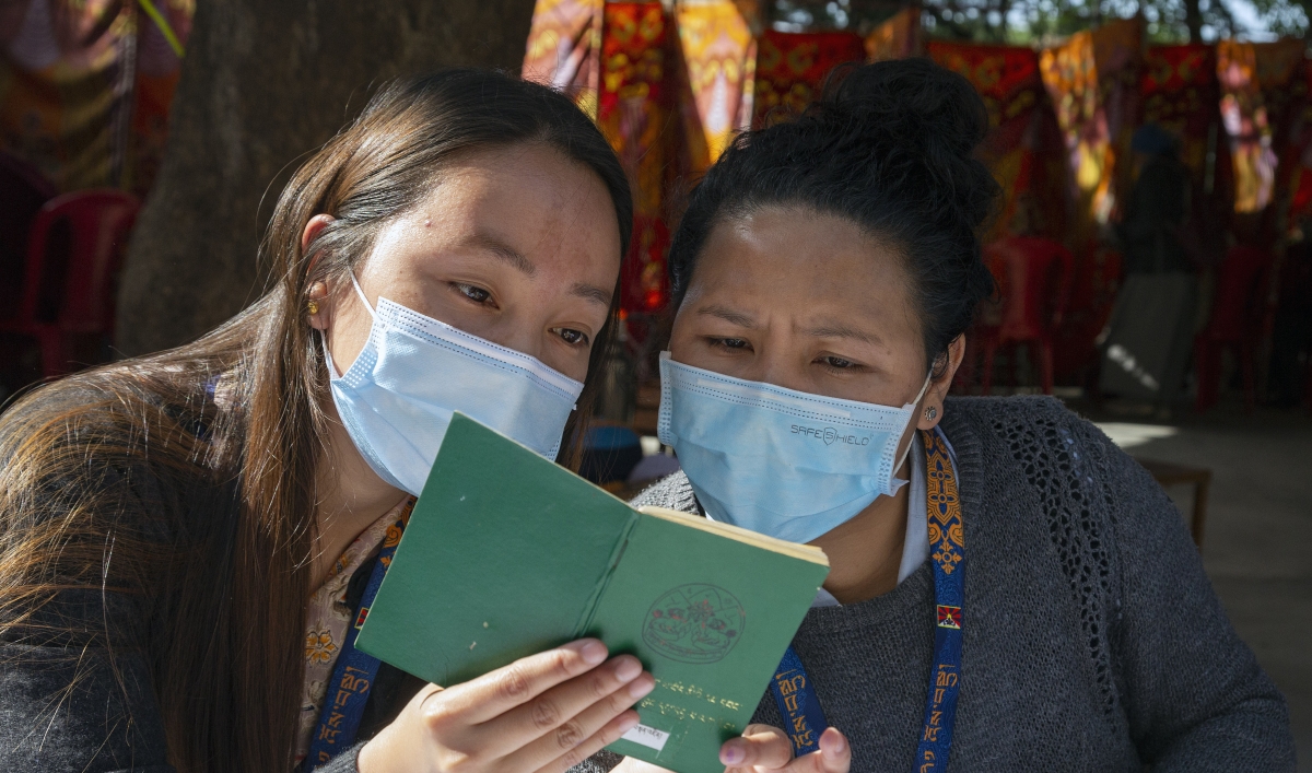 Exile Tibetan booth officials look at a green book, a necessary document for Tibetans to vote, during the second and final round of voting to elect their parliamentarians and the leader of the Central Tibetan Administration