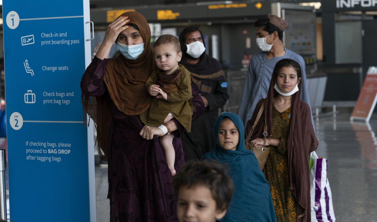 Families evacuated from Kabul, Afghanistan, walk through the terminal before boarding a bus after they arrived at Washington Dulles International Airport, in Chantilly, Virginia, Aug. 27, 2021.