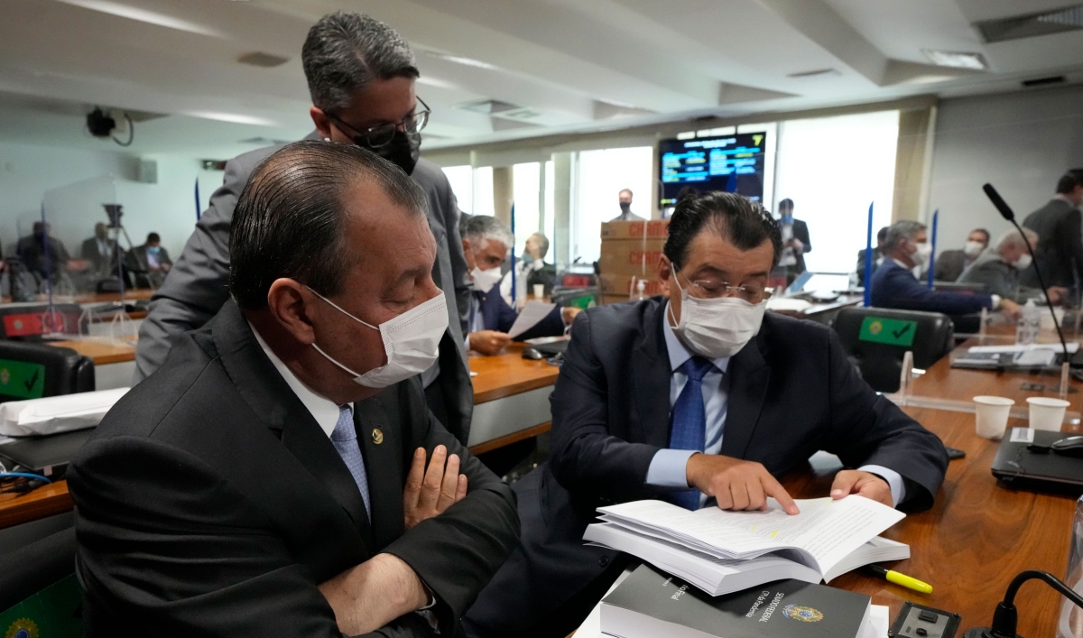 Senators Omar Aziz, sitting left, and Eduardo Braga, right, read a part of a report by a Senate commission that investigated the government's management of the COVID-19 pandemic at the Federal Senate in Brasilia, Brazil, Wednesday, Oct. 20, 2021.