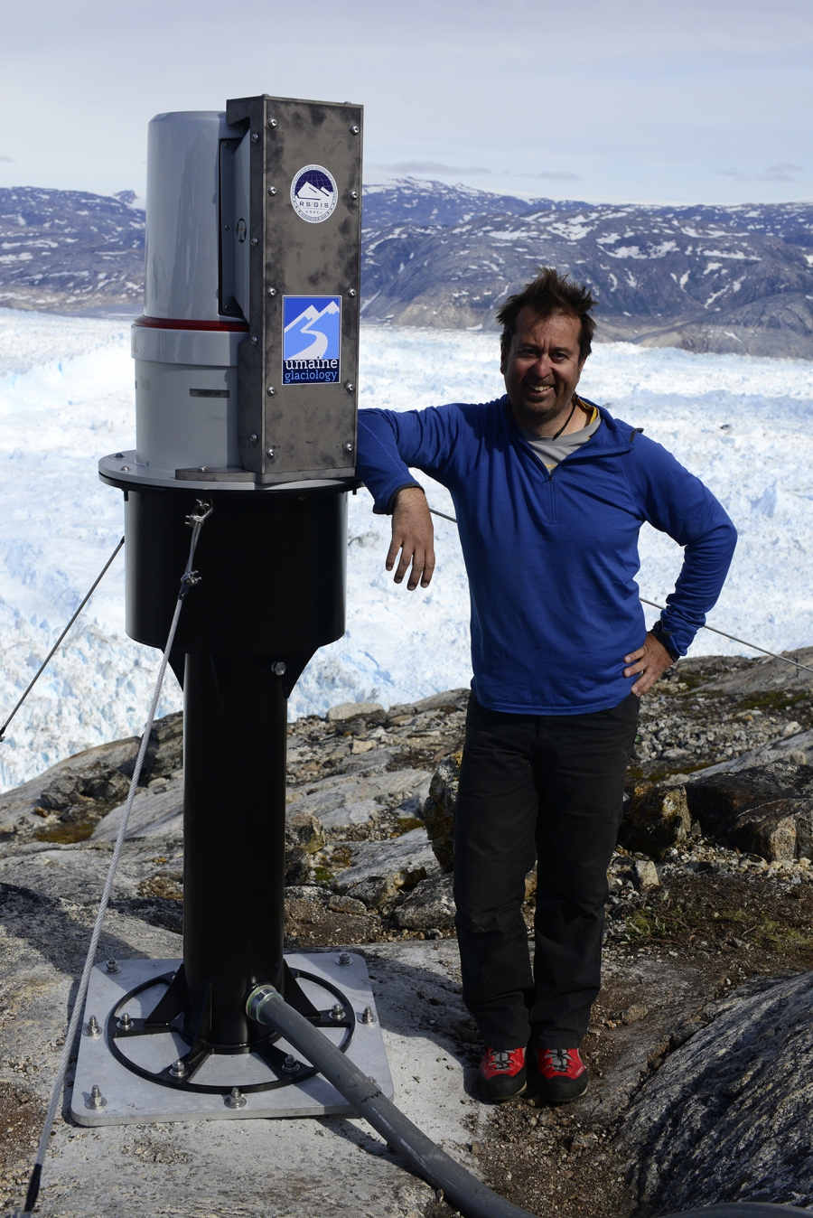 Hamilton Glaciologist Gordon Hamilton from the University of Maine standing next to a new state-of-the-art laser his team has just installed on the rim of Greenland's Helheim glacier. The laser will scan the glacier in unprecedented detail and provide valuable clu